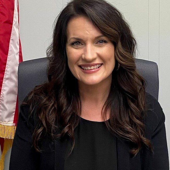 A woman sitting in front of an american flag.