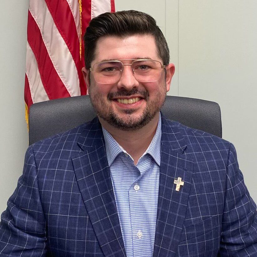 A man in a suit sitting at his desk